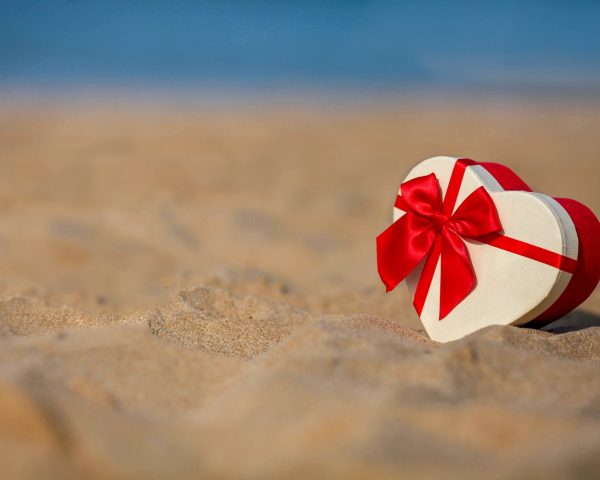 Gift box in the shape of a heart on the sea shore.